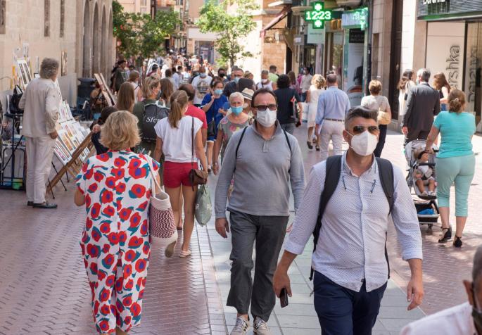 People walking through the streets of Palma wearing masks