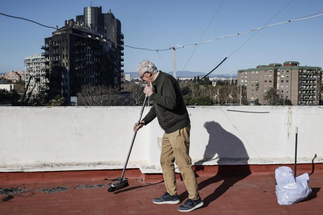 A neighbour clears ash residue from his terrace.